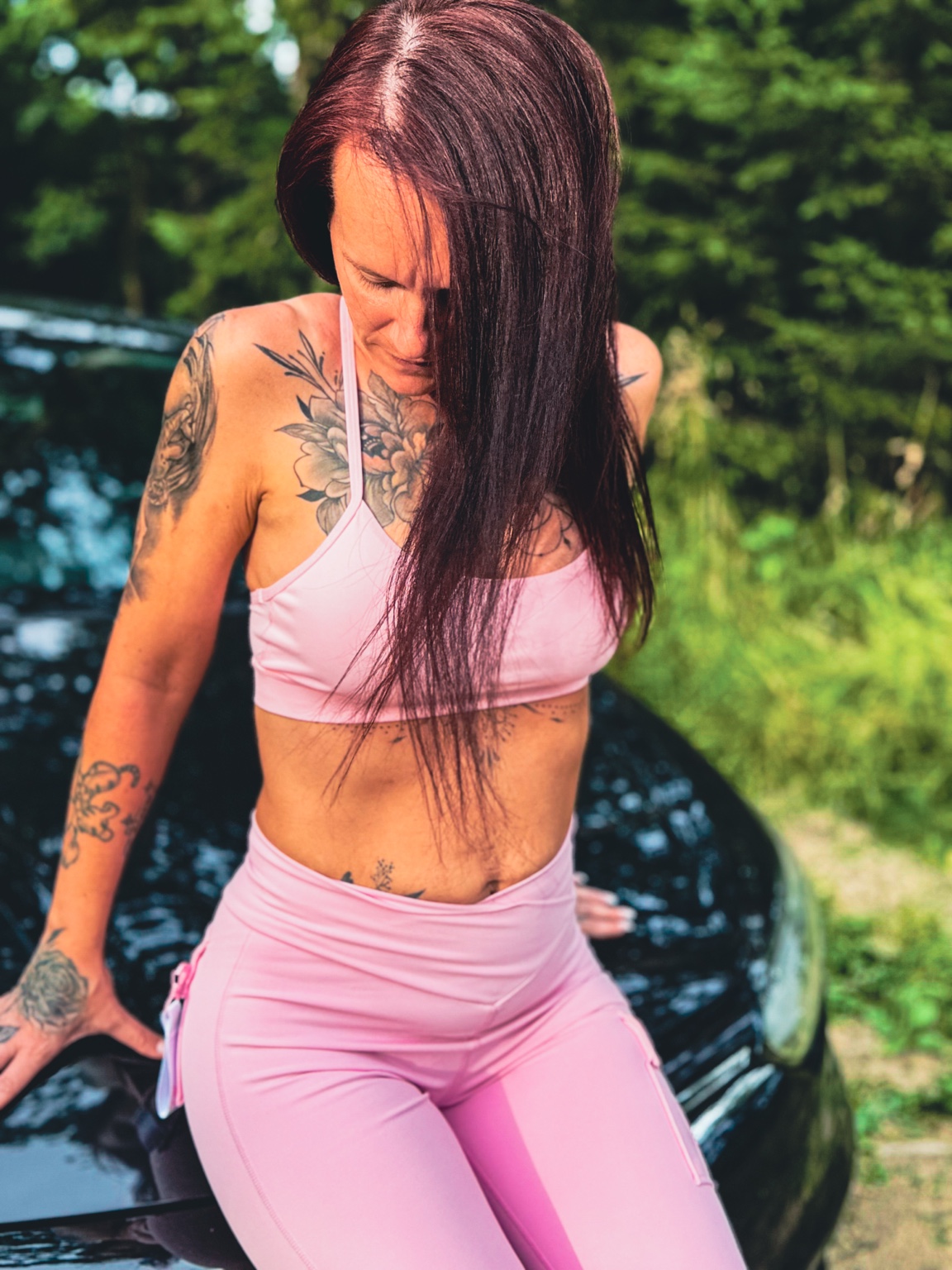 Ruhiges Porträt einer Frau in Rosa vor einem Auto